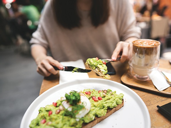 photograph of person with long hair eating avocado on toast